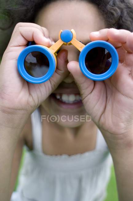 Chica afrocaribeña usando prismáticos en el parque . - foto de stock