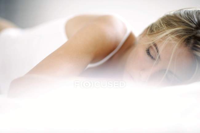 Frau schläft im Bett mit weißen Laken. — Stockfoto