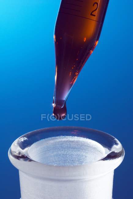 Крупный план капельки жидкости с пипеткой в стеклянную бутылку . — стоковое фото