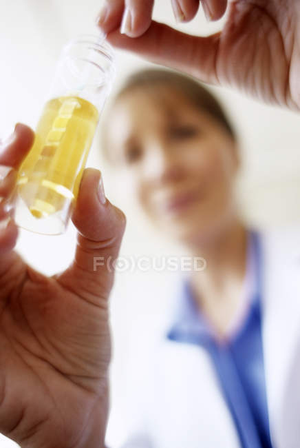 Primer plano de la varilla de prueba múltiple que se coloca en el tubo de muestra de orina por el médico femenino
. - foto de stock