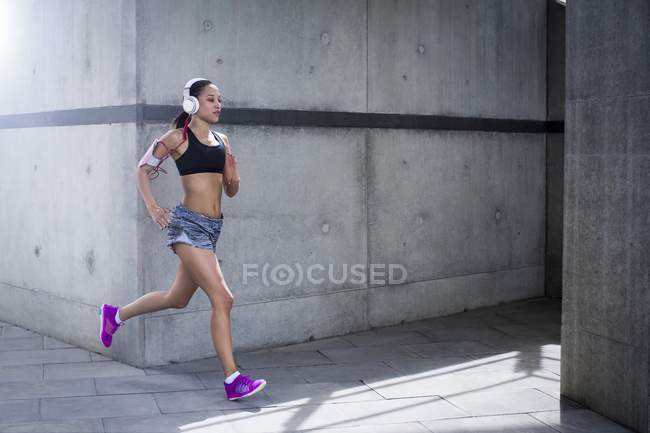 Femme portant des écouteurs courir — Photo de stock