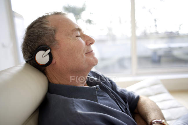 Hombre con auriculares y relajarse en casa - foto de stock