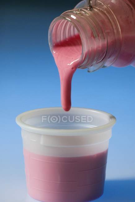Liquid antacid being poured into measuring cup. — Stock Photo