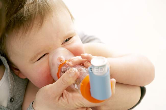 Mutter hilft Baby-Sohn mit Abstandshalter mit Inhalator. — Stockfoto