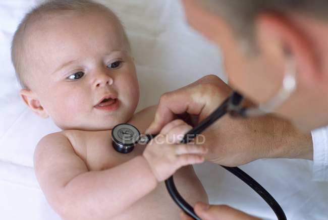 Médecin utilisant stéthoscope pour écouter les battements de coeur de la petite fille nouveau-née . — Photo de stock