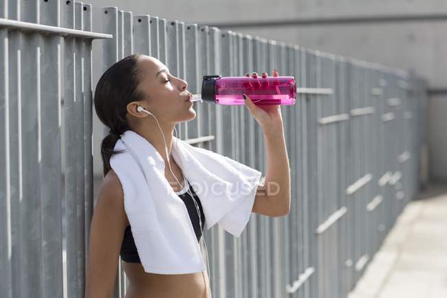 Frau mit Handtuch um den Hals trinkt Wasser — Stockfoto