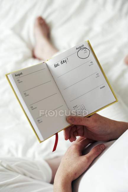 Mulher grávida segurando diário com data de vencimento . — Fotografia de Stock