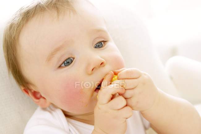 Portrait of baby boy eating crisp. — Stock Photo