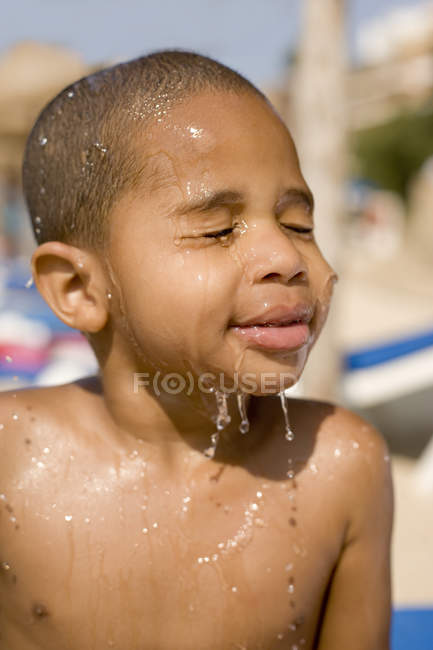 Ragazzo spruzzato con acqua in spiaggia . — Foto stock