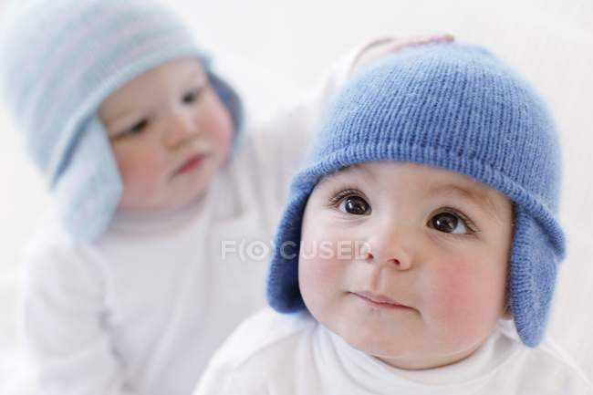 Baby boys in knitted hats playing on white background. — Stock Photo