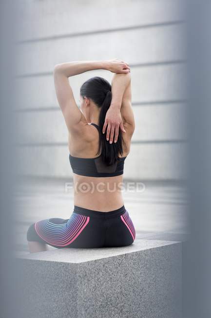 Donna seduta sul muro, stretching — Foto stock