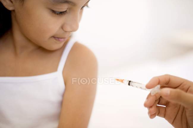 Menina pré-adolescente recebendo injeção de seringa no ombro . — Fotografia de Stock
