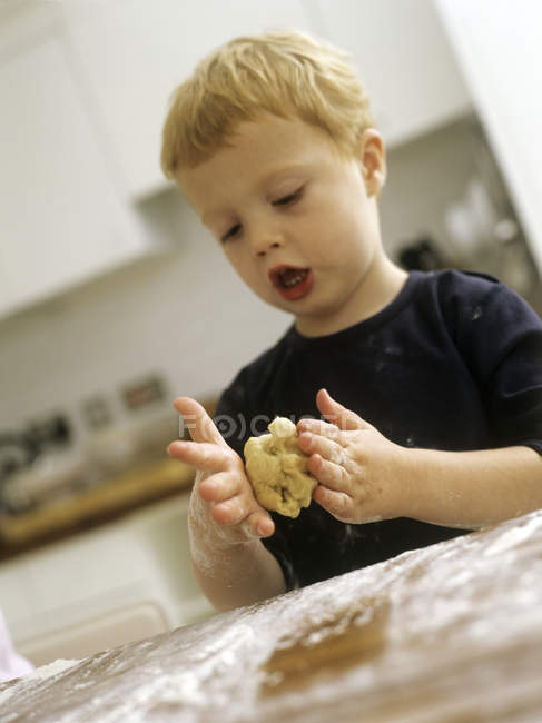 Preschooler boy rolling biscuit dough. — Stock Photo