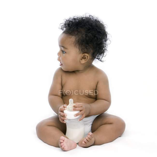 Baby girl sitting with bottle of milk. — Stock Photo