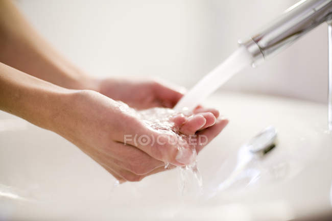 Pessoa lavando as mãos sob água corrente da torneira . — Fotografia de Stock
