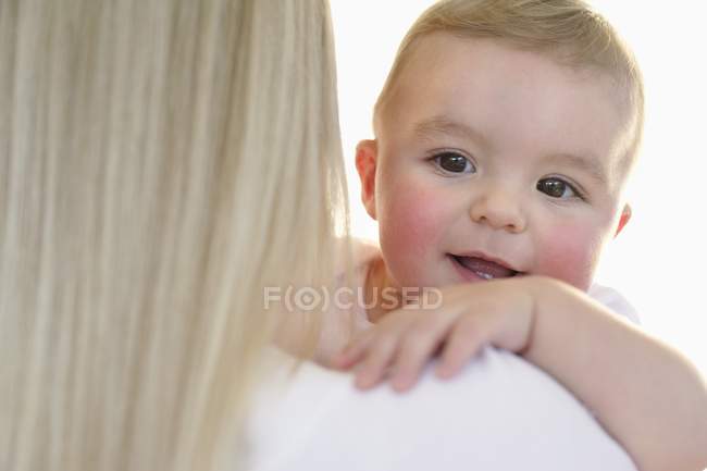 Mother holding baby boy, rear view. — Stock Photo