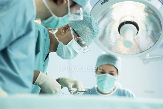 Equipo de cirujanos realizando operaciones en quirófano . - foto de stock