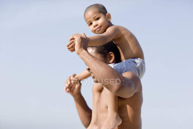 Отец носит сына на плечах на пляже . — стоковое фото