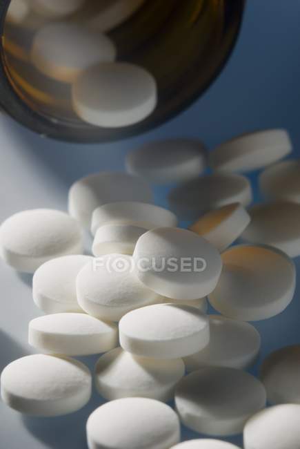 Close-up de pílulas homeopáticas tombando fora da garrafa . — Fotografia de Stock