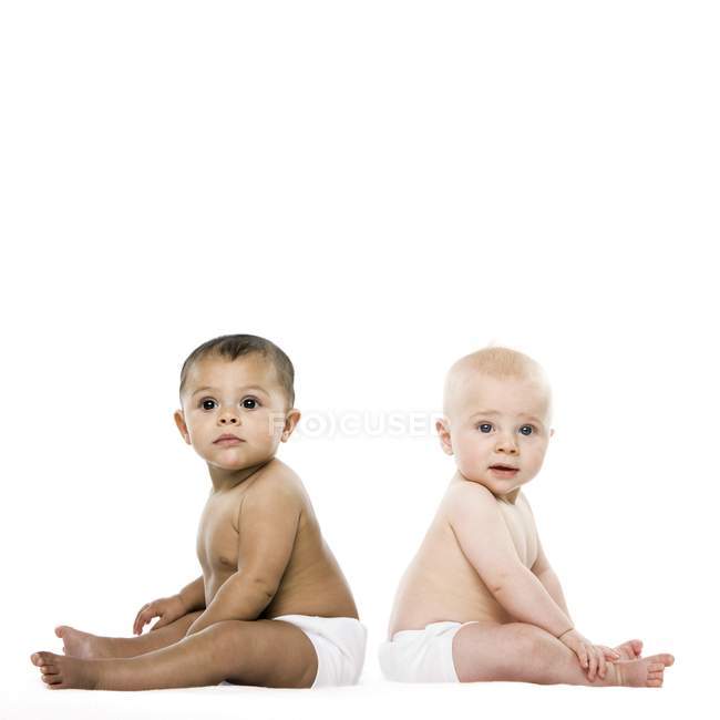 Mädchen und Junge sitzen Rücken an Rücken auf weißem Hintergrund. — Stockfoto