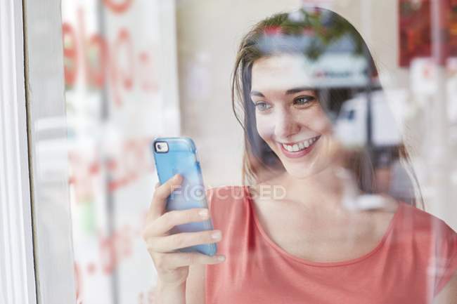 Frau hält Smartphone in der Hand und lächelt. — Stockfoto
