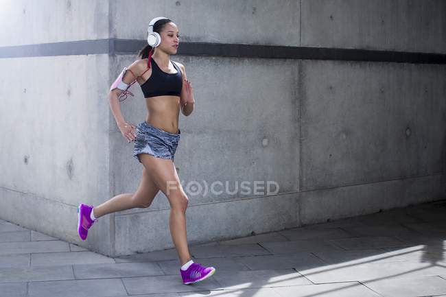 Woman wearing headphones running outdoors — Stock Photo