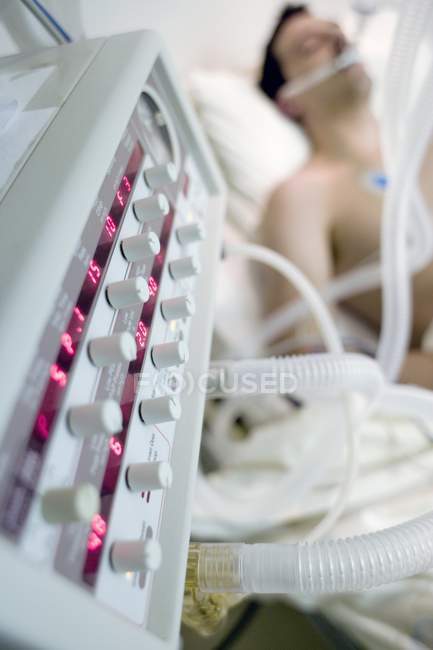 Close-up do ventilador ao lado do homem inconsciente na enfermaria de terapia intensiva hospitalar . — Fotografia de Stock