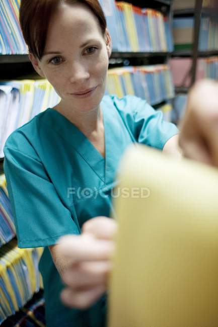 Krankenschwester durchsucht Krankenakte im Abstellraum. — Stockfoto