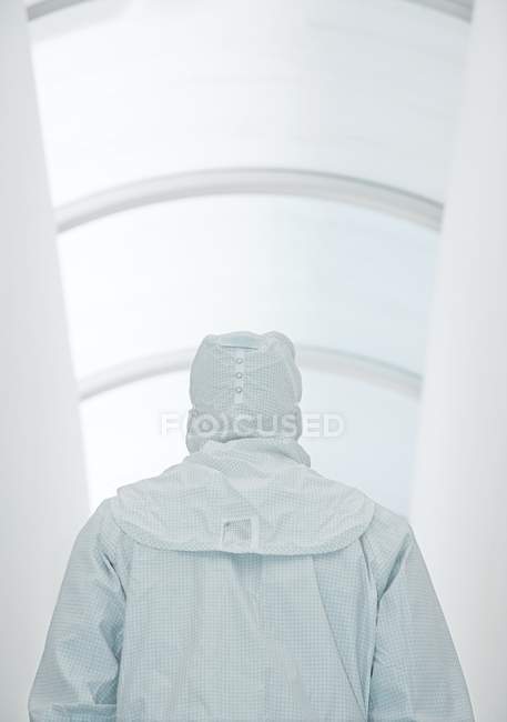 Vista posteriore dello scienziato maschio in tuta isolante bianca nel corridoio . — Foto stock