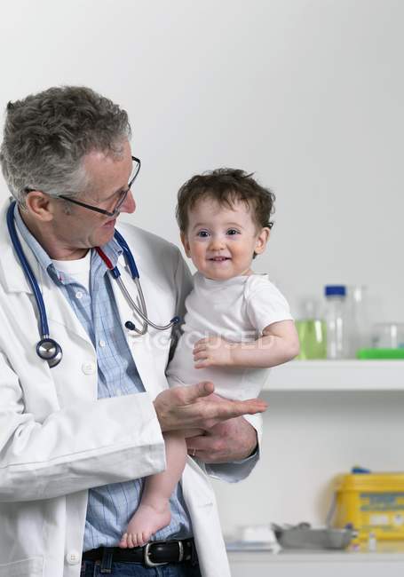 Pediatra masculino sosteniendo niño pequeño . - foto de stock