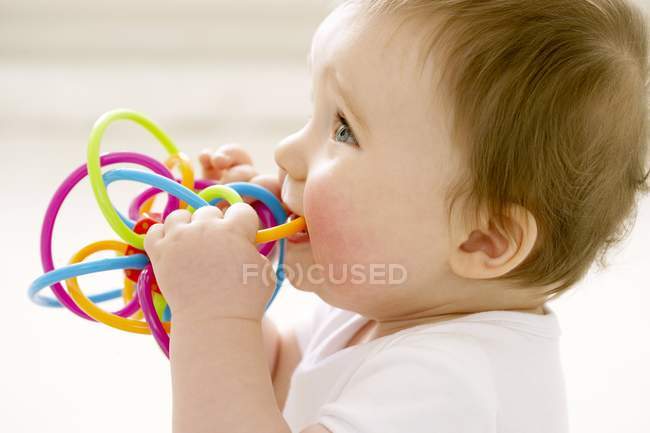 Retrato del bebé masticando el anillo de dentición . - foto de stock