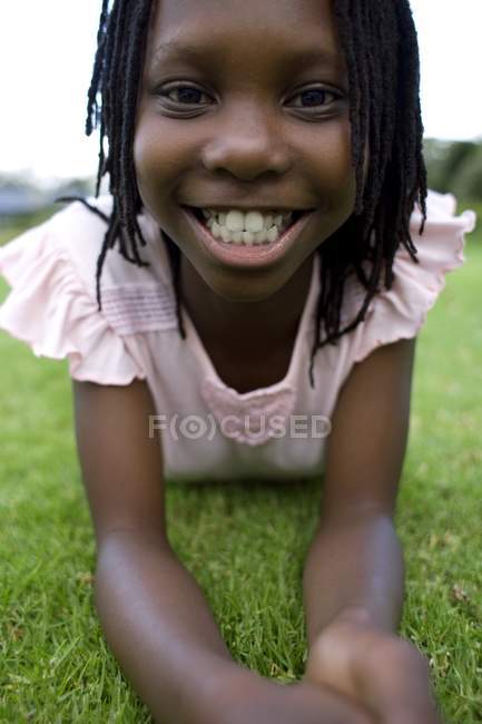 Chica feliz acostada en el frente en hierba verde . - foto de stock