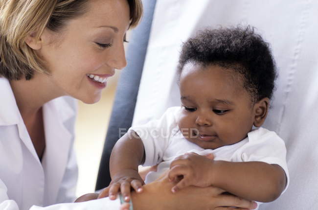 Médecin féminin jouant avec bébé patient à l'examen à la clinique
. — Photo de stock
