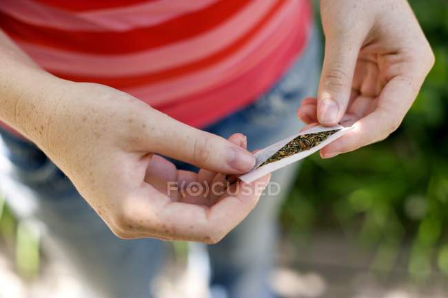 Vista recortada de una adolescente preparando un cigarrillo hecho con tabaco y cannabis
. — Stock Photo