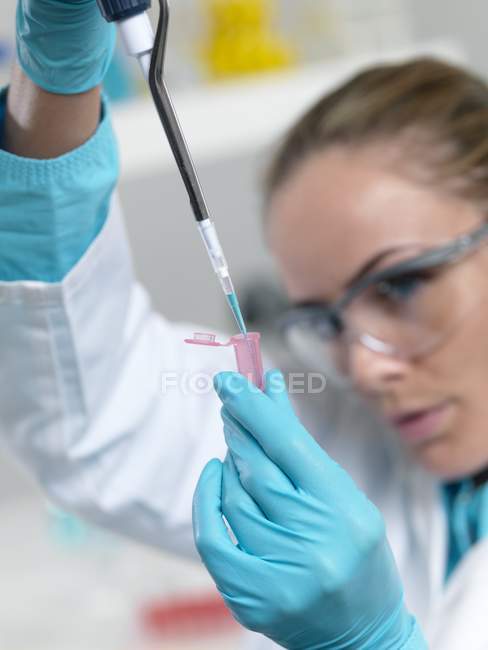 Female researcher pipetting liquid into test tube. — Stock Photo