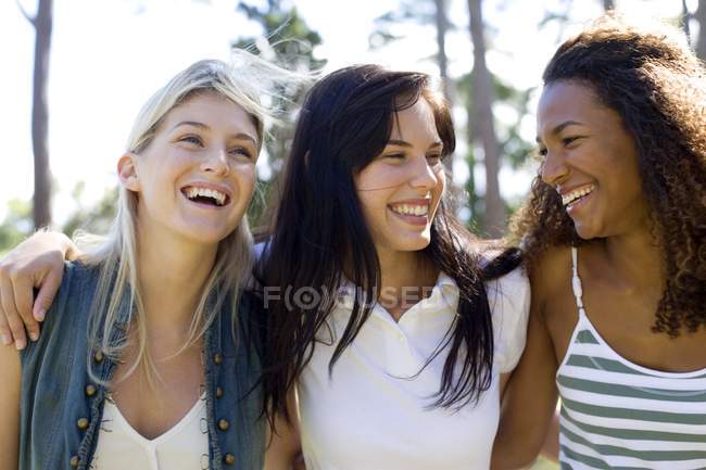 Drei junge Freundinnen spazieren und lächeln im Park. — Stockfoto