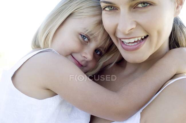 Mãe e filha abraçando e olhando na câmera ao ar livre . — Fotografia de Stock