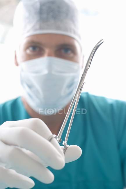 Male surgeon holding artery forceps. — Stock Photo