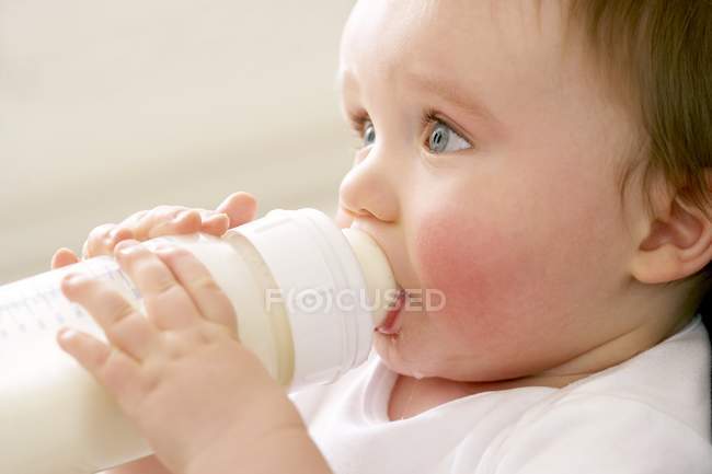 Portrait of baby boy drinking milk from bottle. — Stock Photo