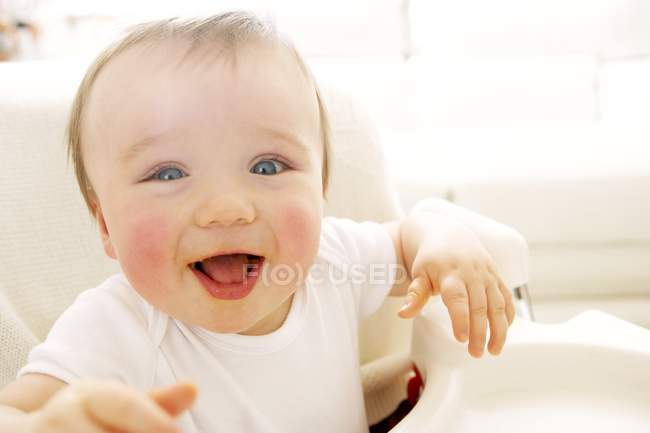 Portrait of happy baby boy in high chair. — Stock Photo