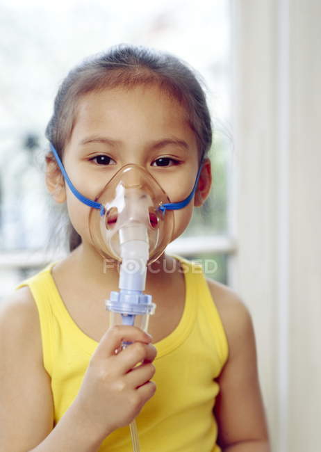 Elementary age asthmatic girl wearing oxygen face mask. — Stock Photo