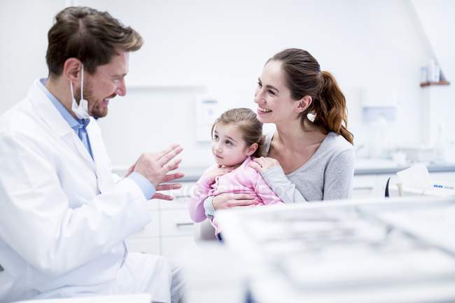 Odontólogo masculino explicando paciente madre en clínica . - foto de stock