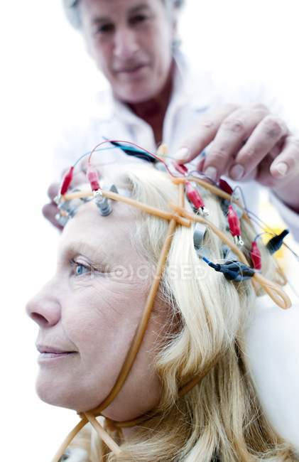 Doctor adjusting electroencephalography equipment on mature patient. — Stock Photo