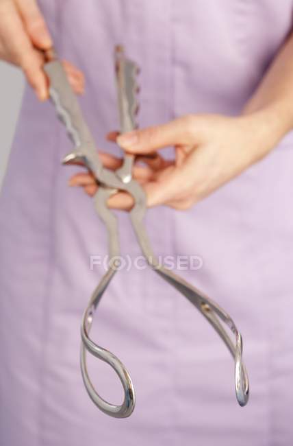 Vista cortada da parteira segurando fórceps obstétricos . — Fotografia de Stock