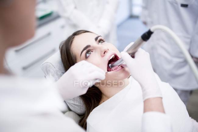 Jovem mulher recebendo tratamento de dentes pelo dentista . — Fotografia de Stock