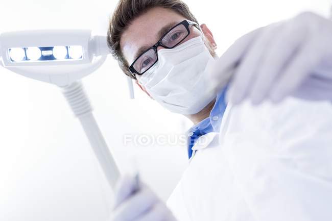 Zahnarzt mit abgewinkeltem Spiegel — Stockfoto