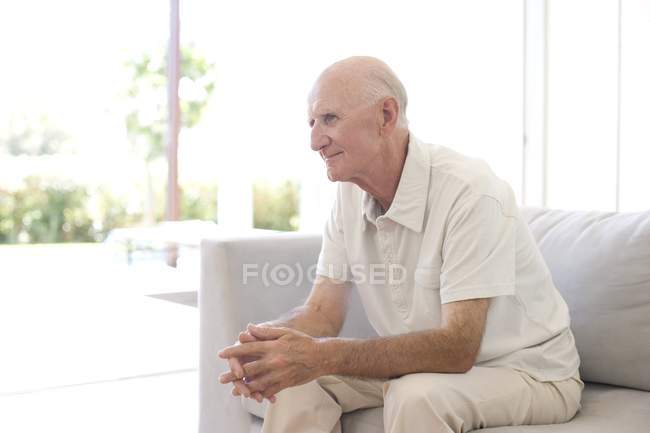 Senior homem sentado sozinho no sofá . — Fotografia de Stock
