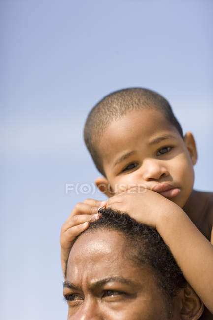 Boy resting head on father against blue sky. — Stock Photo