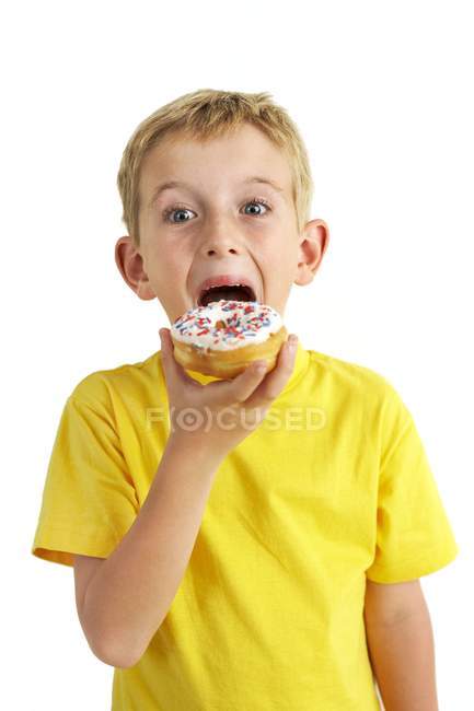 Ragazzo mangiare ciambella su sfondo bianco . — Foto stock