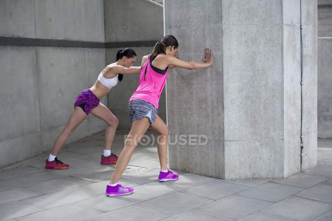 Young women stretching against wall — Stock Photo
